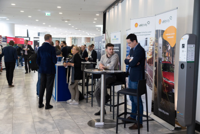 Ausstellungsfläche beim Mobilitätskongress 2022 im CongressCentrum, Personen stehen an Ständen an Stehtischen und sitzen auf Barhockern.