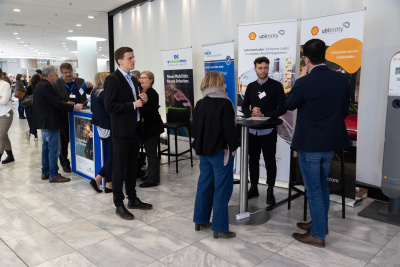 Ausstellung auf dem Mobiliätskongress, Personen stehen vor einem kleinen Stand an Stehtischen