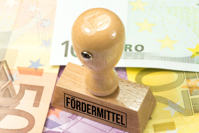 Förderung - Stempel mit Aufschrift 'Fördermittel' auf Geldscheinen Ein Holzstempel mit der Aufschrift 'Fördermittel' steht auf einigen Geldscheinen.