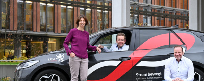 Das Team der Gesch&auml;ftsstelle vor einem Elektroauto