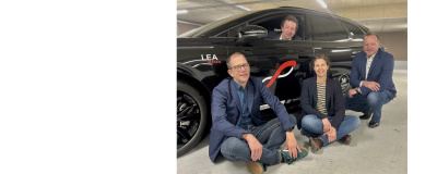 Das Strom bewegt Team vor einem Elektroauto