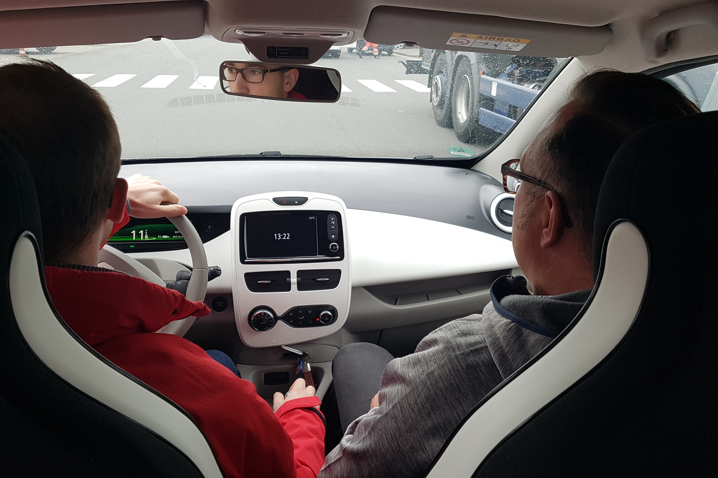 Innenraumfoto eines Renault Zoe mit Blickrichtung vom Rücksitz ins Fahrercockpit. Zwei Männer sitzen vorne.